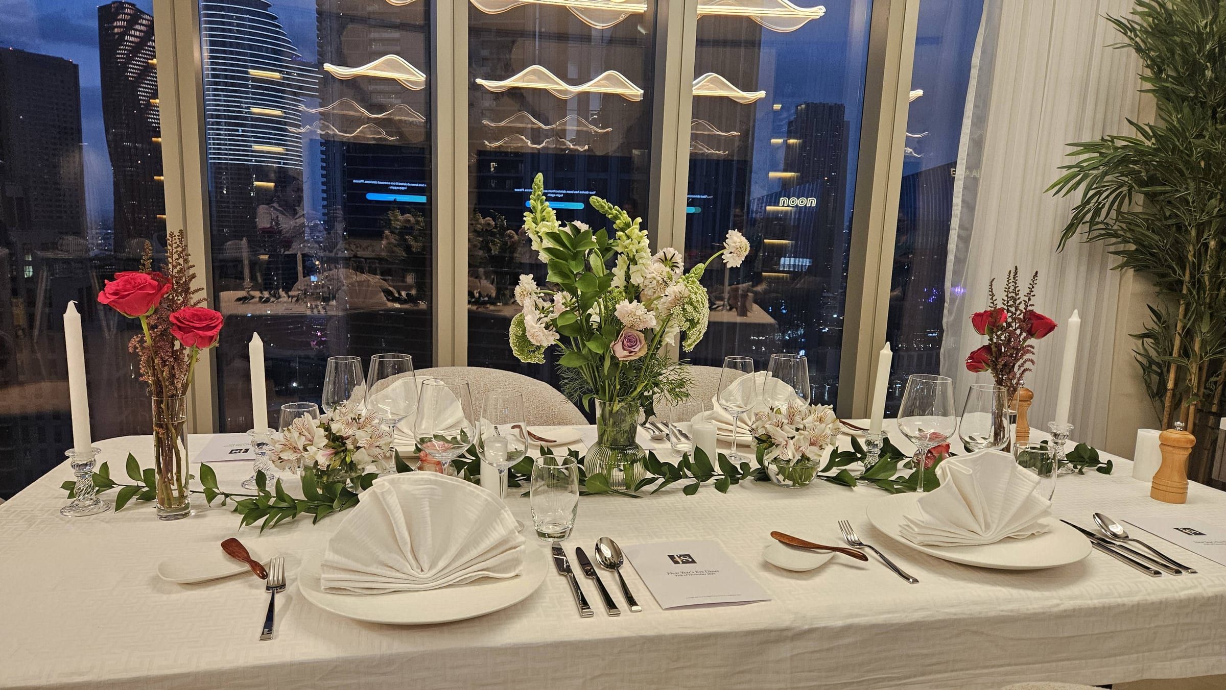 An evening dining table set against the Dubai city skyline